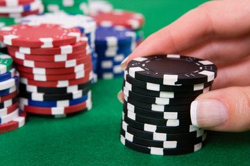 Naklejka premium Female hand putting black poker chips into game.