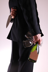Man with two glasses and wine bottle, big knife behind his back