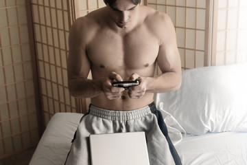 guy going through his cell phone with a laptop in fron of him