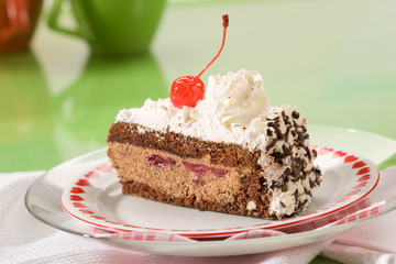 Slice of chocolate cake with cherry on the plate