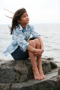 Nine year old girl sitting by lake in summer.