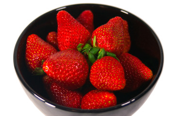 A bowl of bright red strawberries in a black bowl