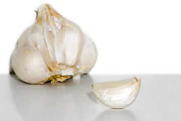 Garlic over white background. Focus on the front peeled clove.