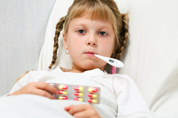 Young girl in bed with thermometer in mouth