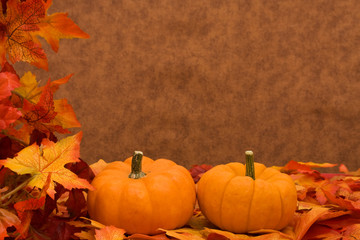 Naklejka na ściany i meble Fall leaves with pumpkin on brown background, fall harvest frame