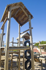 A park next to the beach with a play area for kids containing.
