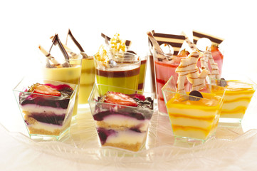 An assortment of colorful mousse desserts in cups.