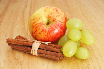 Apple grapes and cinnamon on a wooden board