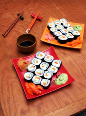sake avocado maki sushi on red and orange trays, wasabi