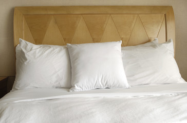 Fototapeta na wymiar Group of several white pillows on a bed with headboard