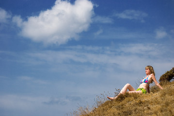 Fototapeta na wymiar Girl sits on a grass and looks in the sky