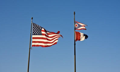 Cleveland, Ohio and USA flags against blue sky.