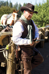 Handsome older cowboy leaning against a fence