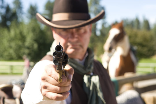 Cowboy aiming gun, focus only on gunpoint, horwe in background
