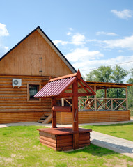 Wooden well stylised semi-antique against a rural landscape