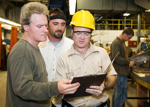 Factory workers and foreman discuss inspection report