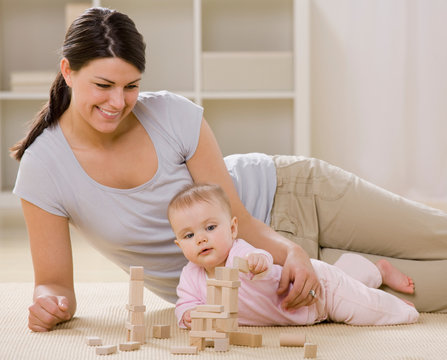 mother and baby playing with blocks on livingroom floor