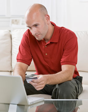 Man Making Online Shopping Purchase On Laptop With Credit Card