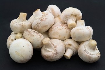 Mushrooms. Heap of champignons on a black background