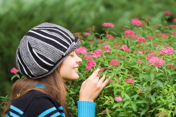 Beautiful woman with hat smelling purple flowers in a garden