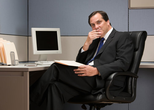 Serious businessman thinking at desk in cubicle