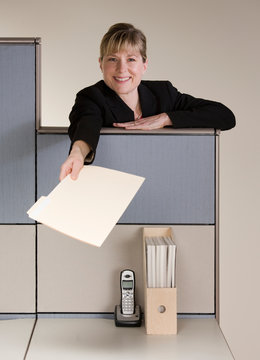 Happy Businesswoman Offering File Folder Over Cubicle Wall