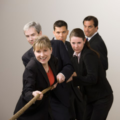 Group of determined co-workers pulling rope in tug-of-war