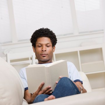 Man relaxing on sofa in livingroom reading a book