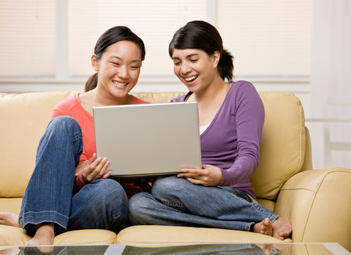 Barefoot friends enjoying using the laptop on sofa in livingroom