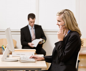 Fototapeta na wymiar Businesswoman talking on headset with co-worker in background