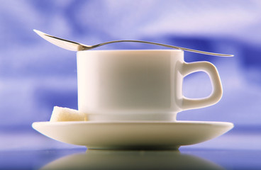 cup of coffee on  plate with dessertspoon