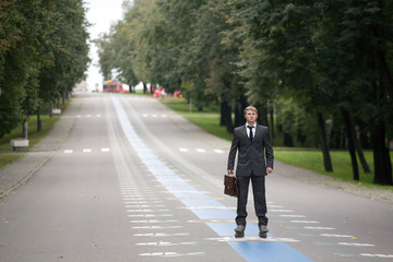 Young businesman on rollerblades standing in park