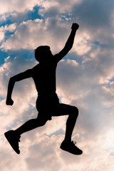 Fototapeta na wymiar Silhouette of young man, jumping, against very cool sky