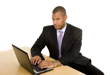 A nice looking black man in a suit sitting at a desk working