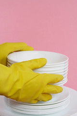 hands with yellow gloves holding white dishes