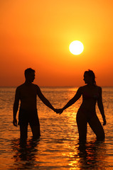 Pair silhouette keeps for hands in sea on sunset