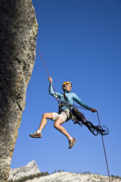 Female rock climber rappelling.