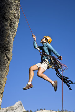 Female rock climber rappelling.