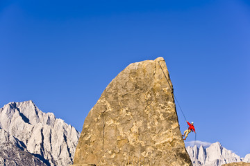Rock climber rappelling from the summit of a rock spire.
