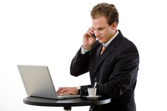Businessman working on laptop and calling on phone,
