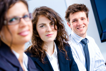 Happy young business people sitting side by side, smiling.