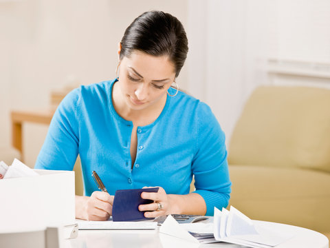 Woman writing check from checkbook to pay monthly bills
