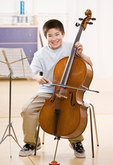 Musician practices performing on cello with sheet music © AVAVA