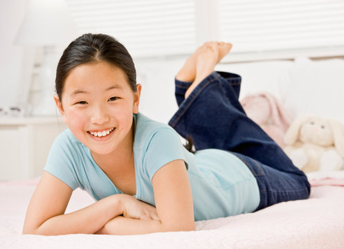 Happy, confident girl laying on bed in bedroom