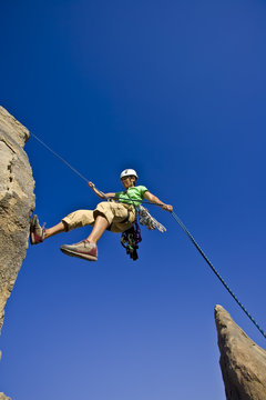 Rock climber rappelling from the summit of a rock spire.
