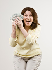 Wealthy woman excitedly holding group of twenty dollar bills