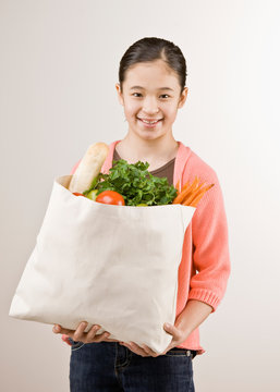 Girl holding grocery bag full of fresh wholesome fruits