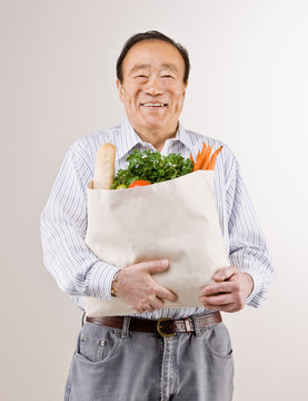 Man holding grocery bag full of fresh fruits and vegetables