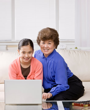 Granddaughter listening to grandmother explain how to use laptop