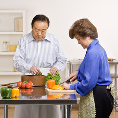 Man preparing salad with wife in kitchen for dinner